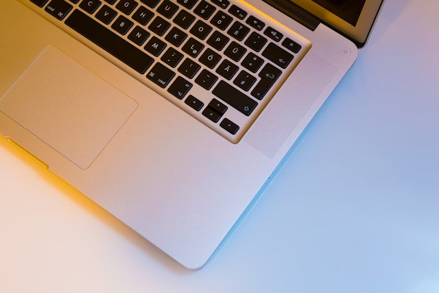 Refurbished MacBooks collection banner showing an overhead, close-up view of an open silver Apple MacBook laptop and its black keyboard layout.