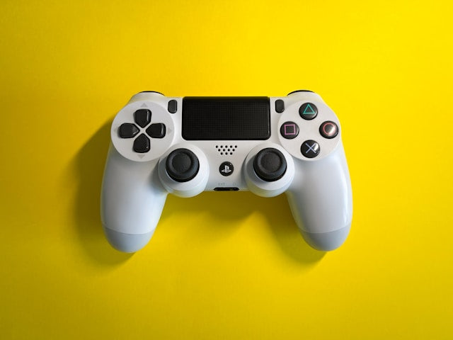 Best selling refurbished electronics banner featuring a white PlayStation DualShock 4 wireless controller centered on a vibrant, solid yellow background.