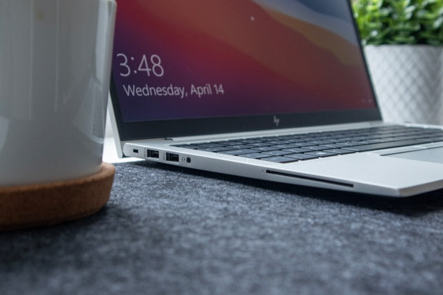 Refurbished HP laptops collection banner showing an open silver HP laptop on a gray desk mat next to a coffee mug.