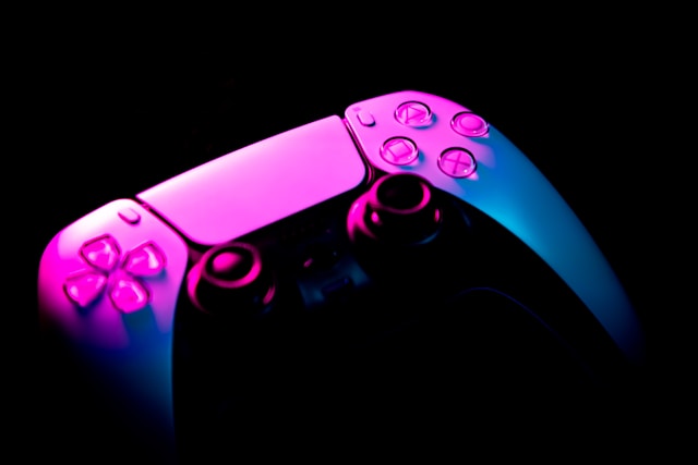 Refurbished gaming consoles collection banner featuring a close-up of a gaming controller illuminated by vibrant pink and blue neon lights against a dark background.